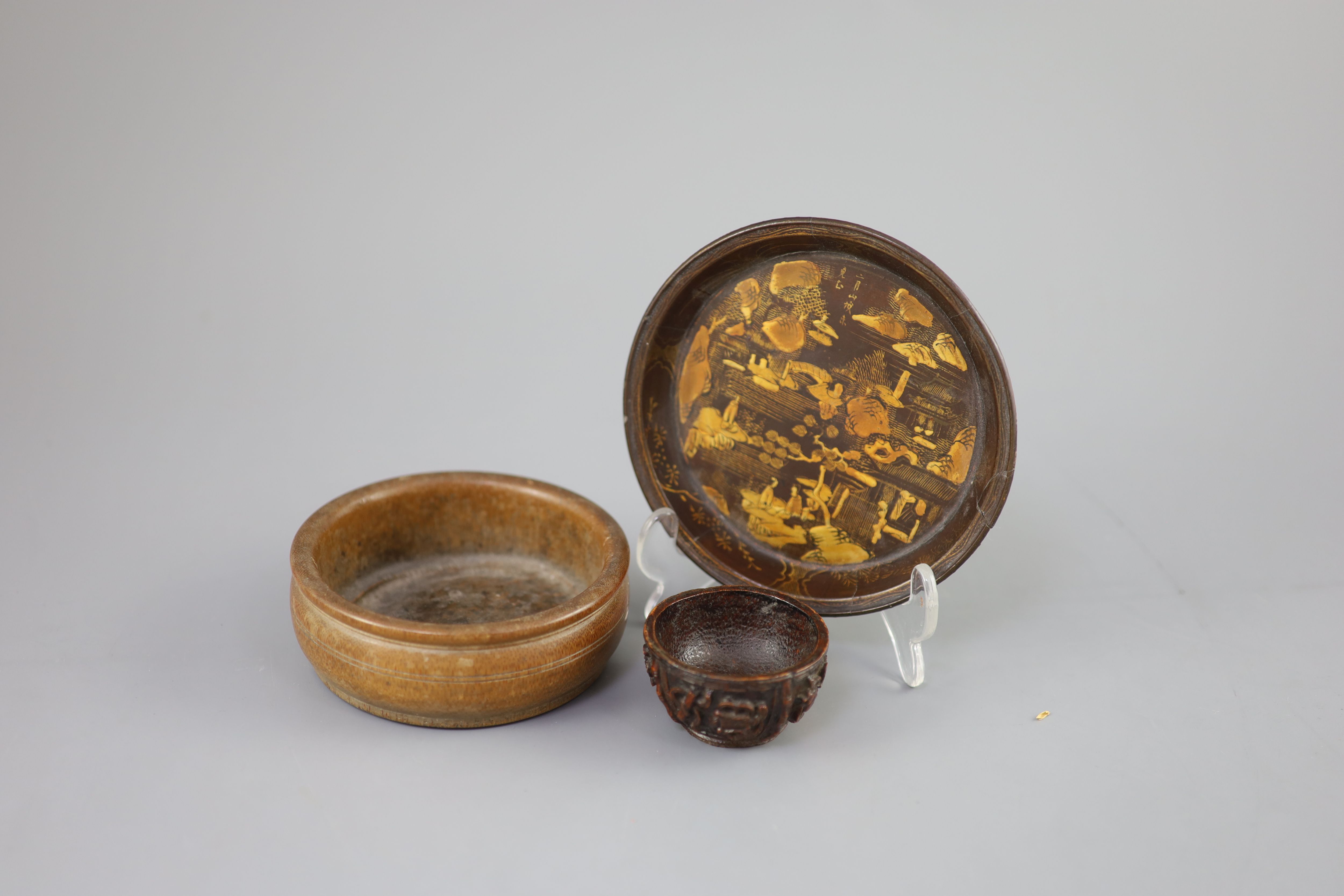 A Chinese carved bamboo cup, a plain bamboo brushwasher, 18th/19th century and a gilt decorated lacquer saucer dish, 17th century,
